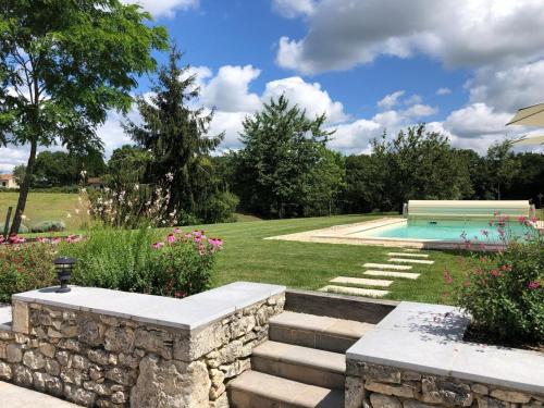 un jardin avec un mur en pierre et une piscine dans l'établissement Aux charmes d'angely, à Naussannes