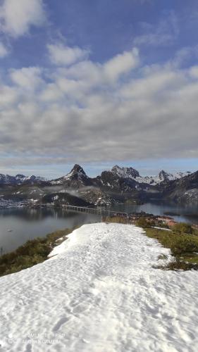 a snow covered field with mountains and a body of water at Abuela Carmen in Riaño