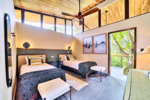 two beds in a room with windows at Conga Boutique Hotel in Puerto Viejo