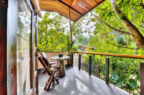 a balcony of a tree house with a table and chairs at Conga Boutique Hotel in Puerto Viejo