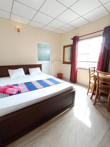 a bedroom with a bed and a table and chairs at The Golden Bow in Seeduwa