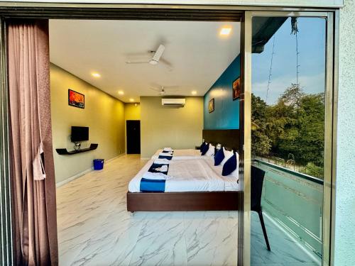 a bedroom with a bed and a large window at Golden Pearl Resort By Gemstone Hospitality in Alibag