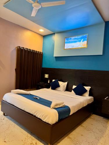 a bedroom with a large bed with a blue wall at Golden Pearl Resort By Gemstone Hospitality in Alibag