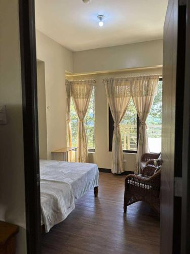 ein Schlafzimmer mit einem Bett, einem Stuhl und einem Fenster in der Unterkunft Outlook Ridge Residences VY in Baguio City