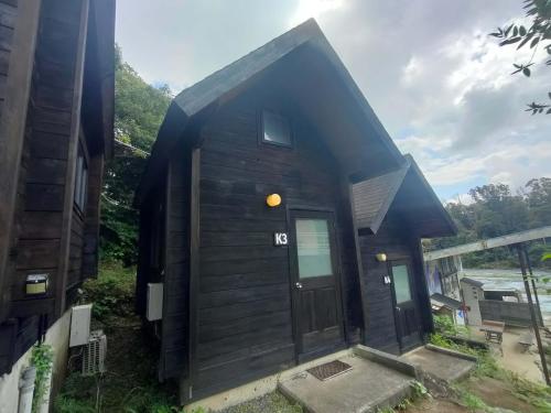 a black cabin with a door on the side of a house at 南伊豆ランドホピア Minami Izu Land Hopia in Minamiizu