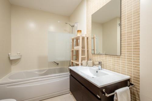 een badkamer met een wastafel, een bad en een spiegel bij Bay View T1 - By Smarthomes in São Martinho do Porto