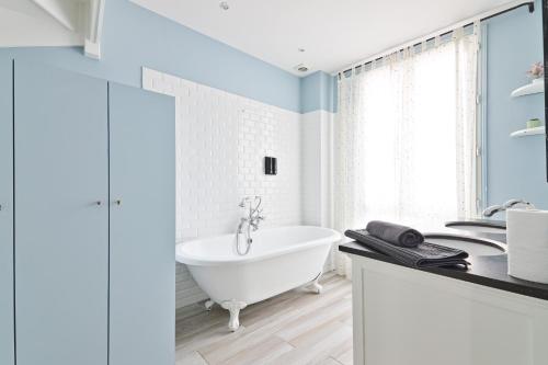 une salle de bain avec une baignoire blanche et un lavabo dans l'établissement Superb Appartement Quartier Tour Eiffel 8 Free Netflix, à Paris