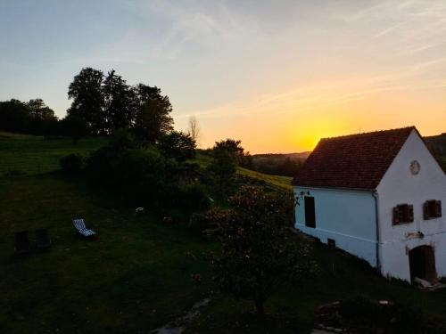 a small white house in a field at sunset at Pferdehof in der Oststeiermark 