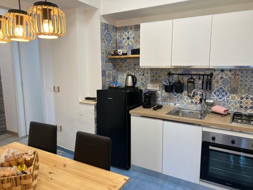 a kitchen with a table and a black refrigerator at Pompei Sunday Estate Exclusive Apartaments in Pompei