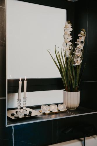a black counter with candles and a vase with white flowers at Zapato Apartment Tuzla in Tuzla