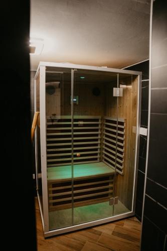 a glass cabinet with a green seat in a room at Zapato Apartment Tuzla in Tuzla