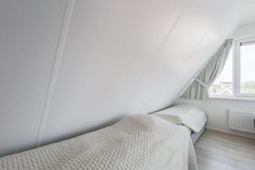 a white bedroom with a bed and a window at Weststraat 22 - Ouddorp - Appartement West 3P in Ouddorp