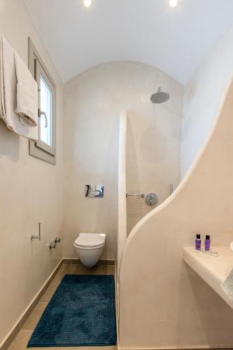 a white bathroom with a toilet and a shower at Santorini Villatzio Suites in Mesaria