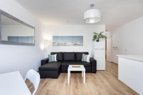 Una sala de estar con un sofá negro y una mesa. en Ocean view & Pool Los Cristianos Summerland, en Los Cristianos