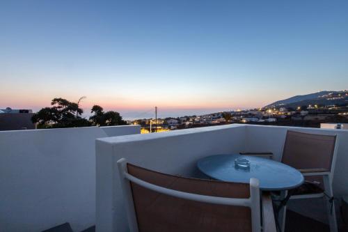 a table and chairs on a balcony with the sunset at Santorini Villatzio Suites in Mesaria