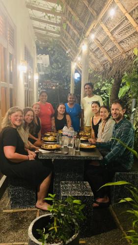 a group of people posing for a picture at a table at Ayubowan Hiriketiya in Dickwella