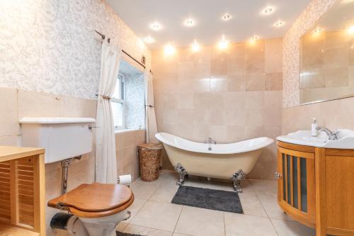 a bathroom with a tub and a toilet and a sink at Country Farmhouse Sleeps 13 & New 8Seater Hot Tub in Otley