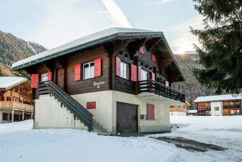 a building with red doors and stairs in the snow at Chalet Daheim - Ferienwohnung OG in Reckingen - Gluringen