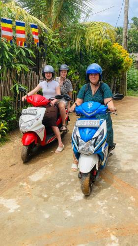 three people are riding motorcycles on a dirt road at Ayubowan Hiriketiya in Dickwella