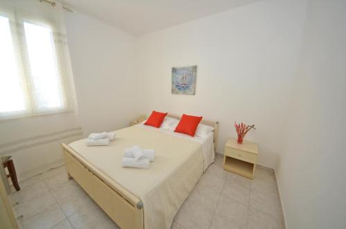 a white bedroom with a bed with red pillows at La Casa Dei Marini in Lido Marini