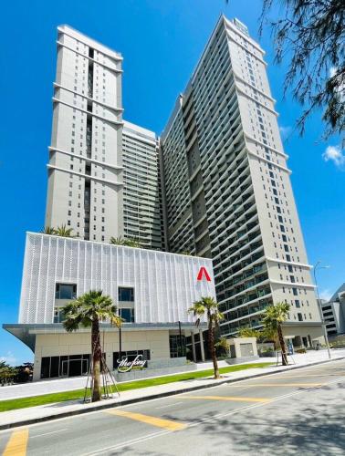 two tall buildings with palm trees in front of a street at The Song Luxury Vung Tau - Khang Apartment 1 in Vung Tau