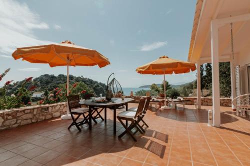 a patio with a table and chairs and umbrellas at Kastraki Sea View in Tolo