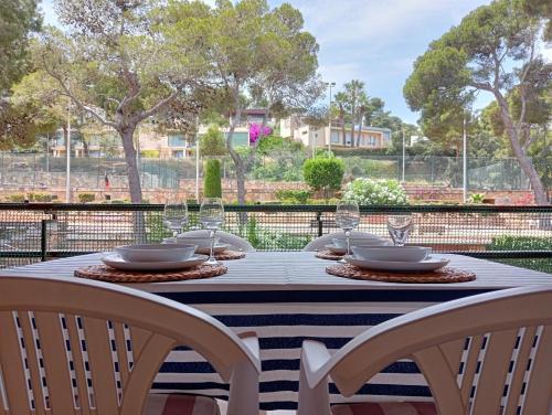 a table with chairs and plates and wine glasses at Apartamento EDEN MAR I by HR COSTABRAVA in Calonge