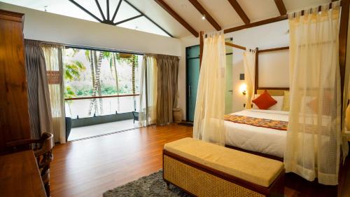 a bedroom with a bed and a large window at Sakthi River Resort in Pollāchi