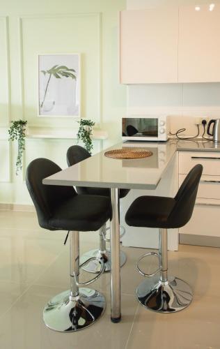 a kitchen with a table and two black chairs at Spacious One Bedroom Apartment in Caesar Resort & SPA, Long Beach in Perivolia tou Trikomou