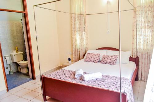 a bedroom with a canopy bed and a bathroom at Mi Casa Su Casa in Mtwapa
