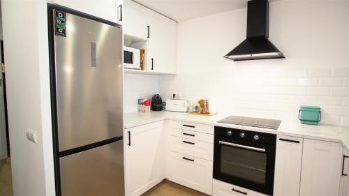 a kitchen with a stainless steel refrigerator and white cabinets at Apartamento EDEN MAR I by HR COSTABRAVA in Calonge