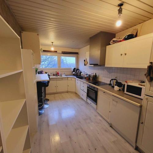 une cuisine avec des armoires blanches et un plancher en bois dans l'établissement 14 allée du Gacet, à Rennes