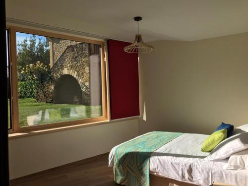 a bedroom with a bed and a large window at Le petit fort in La Roque-Gageac