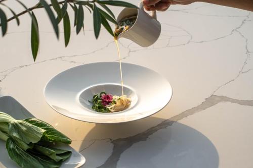 a person pouring sauce into a plate of food at Vesta Grand Central Udaipur in Udaipur
