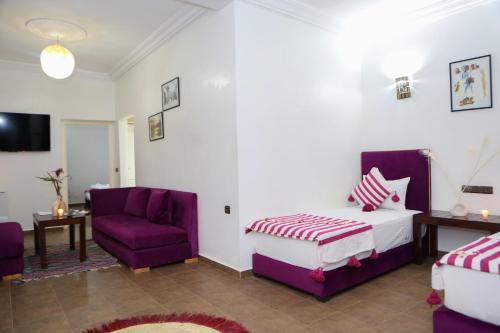 a hotel room with a bed and a purple chair at Weedan Hôtel&Spa Marrakech in Oulad Snaguia