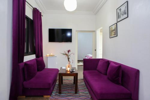 a living room with purple couches and a table at Weedan Hôtel&Spa Marrakech in Oulad Snaguia