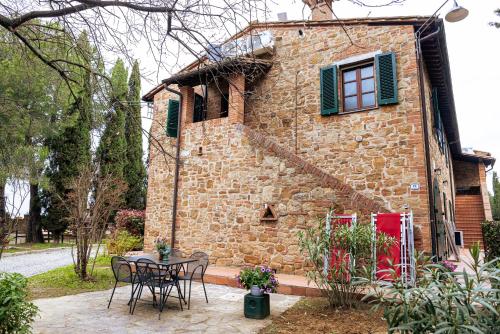 a stone house with a table and chairs in front of it at Borgo Il Poggio Agriturismo in Montaione