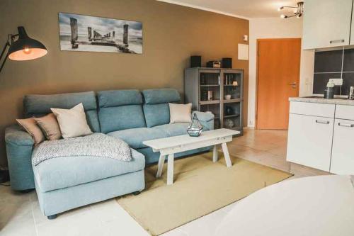 a living room with a blue couch and a table at Bucht 9 in Prerow