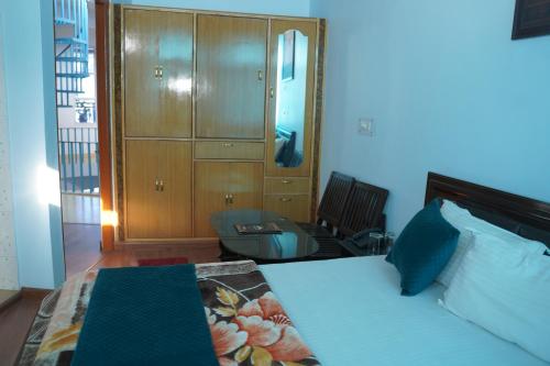a bedroom with a bed and a cabinet and a chair at Hotel Chail Hill & Restaurant in Chachyot
