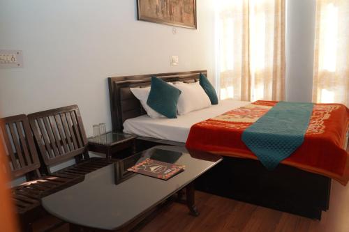 a bedroom with a bed with a desk and a table with a bed sidx sidx at Hotel Chail Hill & Restaurant in Chachyot
