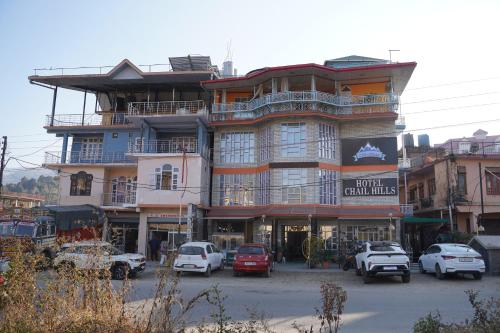 a large building with cars parked in front of it at Hotel Chail Hill & Restaurant in Chachyot
