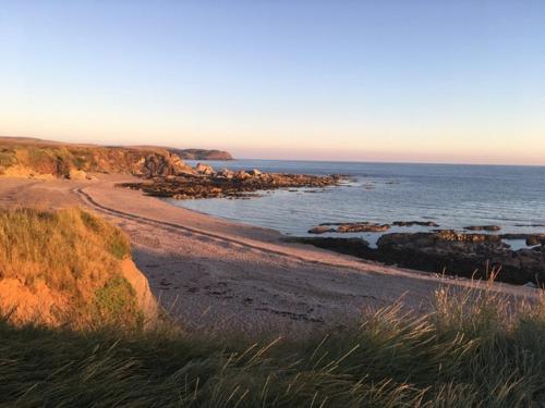 a beach with rocks and the ocean in the background at Badgers Den, a beautiful log cabin in a secluded valley close to the beach in Bantham
