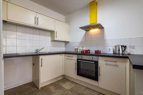 a kitchen with white cabinets and a stove top oven at Charming 1-bed Flat in Eastwood in Eastwood