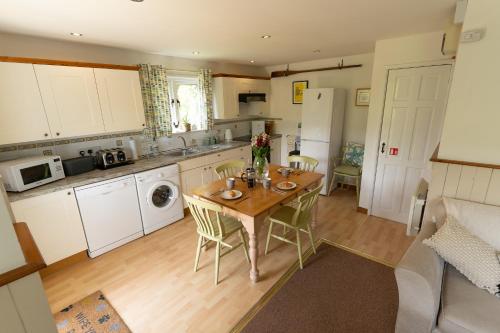 a kitchen with a wooden table with chairs and a sink at Badgers Den, a beautiful log cabin in a secluded valley close to the beach in Bantham
