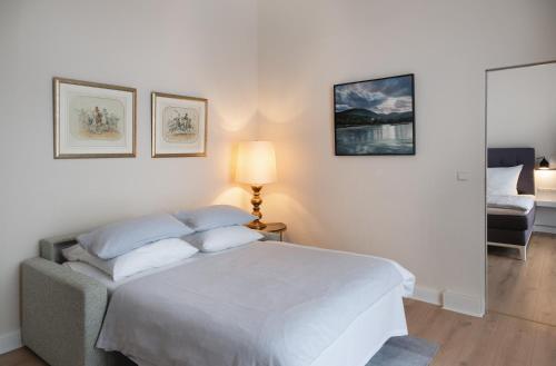 a white bedroom with a bed and a lamp at Rheinhotel Dreesen in Bonn