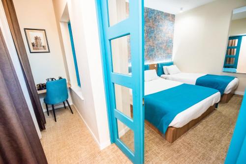a room with two beds and a table and a chair at City Inn - Boutique Hotel Tbilisi in Tbilisi City
