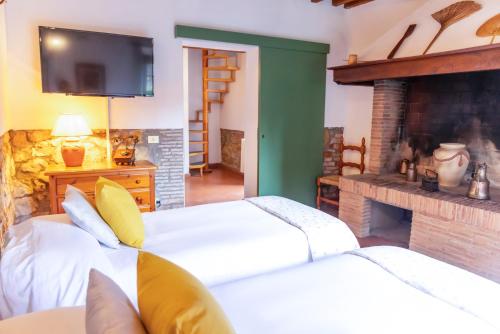 two beds in a room with a fireplace and a tv at Borgo Il Poggio Agriturismo in Montaione
