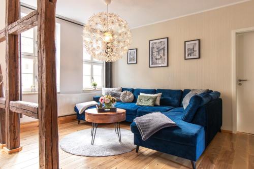 a living room with a blue couch and a chandelier at Apartmenthaus Mathilde in Quedlinburg