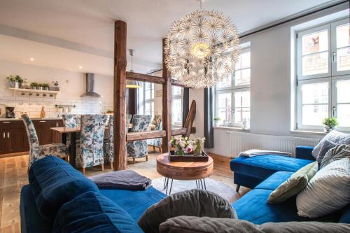 a living room with blue couches and a chandelier at Apartmenthaus Mathilde in Quedlinburg