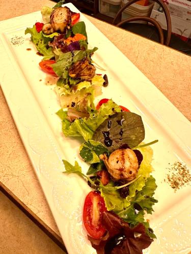 a white plate with a salad on a table at Grace Homestay in Yujing